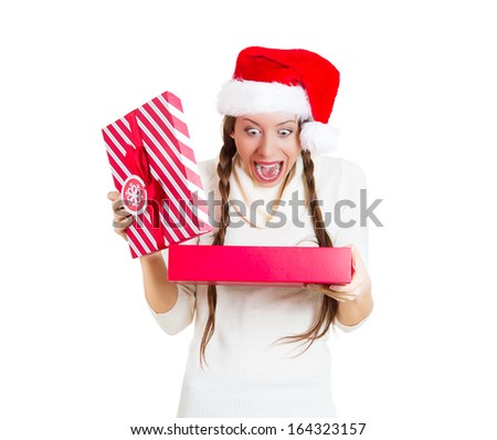 Closeup portrait of a young beautiful excited woman wearing red santa claus hat, opening gift box and super happy at what she gets, isolated on white background. Positive emotions, facial expressions