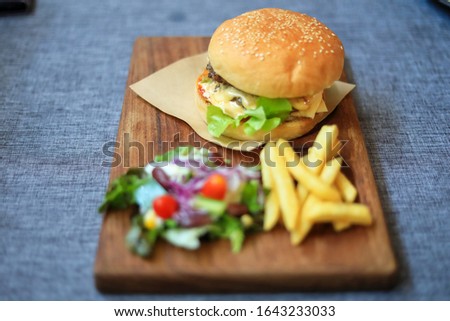 Home made hamburger beef  lettuce  cheese french fries and salad. Selective focus only burger blur background.