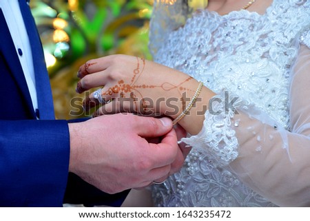 The bridegroom wears a chain of gold in her hands tattooed with henna