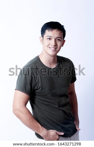 A Portrait of young asian wearing a green tshirt and white jeans showing gesture sign or devices