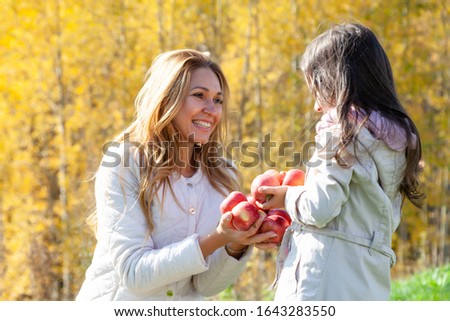 Beautiful mother, daughter play with red apples
