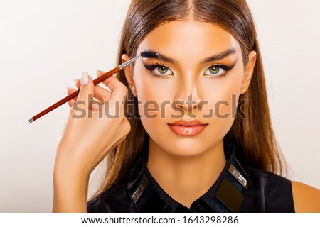 Care beauty eyebrow. Beautiful Young Woman Portrait.  Makeup Artist does Face and Eyebrow Makeup. Perfect Bushy Eyebrows. Glossy Peach Lips. Makeup. Beautiful woman with brow brush in hand.   Royalty-Free Stock Photo #1643298286