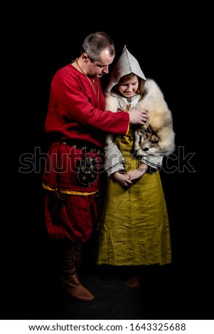 Father and daughter teenager dressed in costumes of the Viking era, 10-11 century, region - Sweden, recreated based on archaeological finds. Father straightens his daughter's clothes