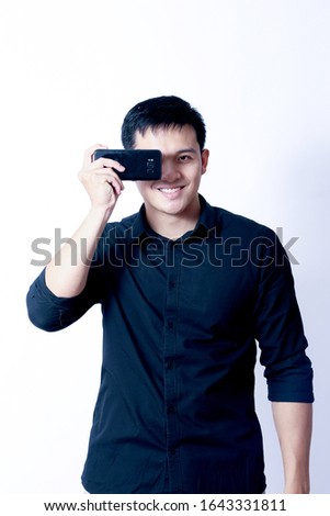 A Portrait of young asian man wearing Black Shirt showing gesture sign or devices
