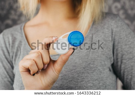 blonde girl holds case for storing contact lenses for eyes, close-up