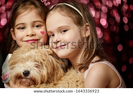 two adorable little girls with dog are posing on the shiny carnival background