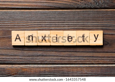 Anxiety word written on wood block. Anxiety text on wooden table for your desing, Top view concept.