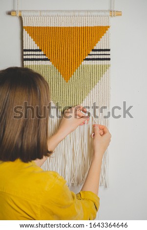 Woman doing macrame craft. Hand-making a cotton rope wall-hanging decor piece, concept of handicraft hobby or handworking