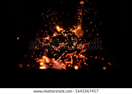 red smoldering embers in a barbecue with flying icters on a black background