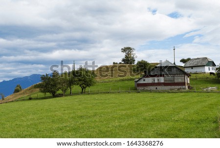 Scenic picture-postcard view with a mountain village in the Carpathian Mountains. Mountain alpine landscape with houses separated by a wooden fence. Beautiful spring field 