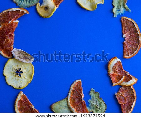 Sliced fruits being dried on racks in electric food dehydrator. blue background. dried apples, oranges, kiwis, bananas. 