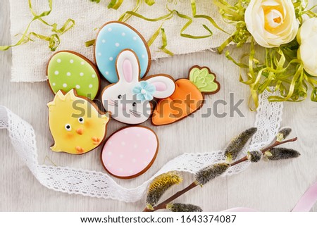 Close up of glazed cookies in shape of lovely bunny, chick, carrot and three eggs lying on table, willow branch, flowers isolated on white background. Cute homemade pastry. Spring holidays concept.