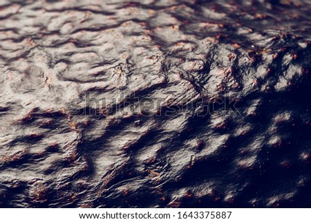 Detail photo of an avocado skin. Brown textured skin of an avocado fruit. Fresh ripe avocado with smooth wavy surface.