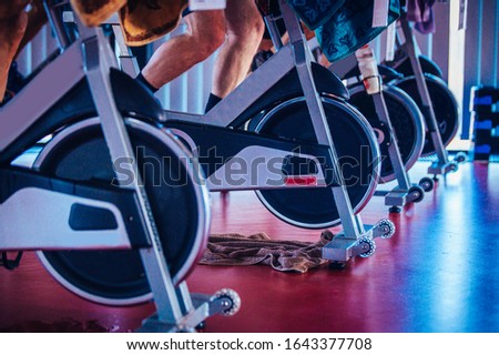 Spinning class, group activity on stationary bike. Team cardio excercise on bicycle. Royalty-Free Stock Photo #1643377708