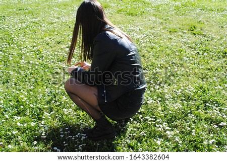 A girl dressed in black picking flowers
