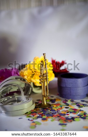 Selective focus. Mini trumpet used in carnival band, in focus. Defocused carnival accessories.Horizontal. Close up view. Text space. White gradient background.