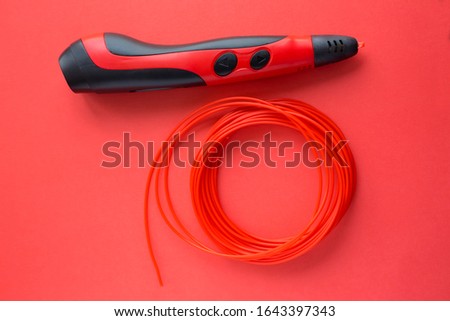 3d printing pens and colorful filaments on red background. Top view