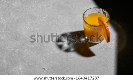 One glass with orange juice on grey background. Tropical summer minimalism concept