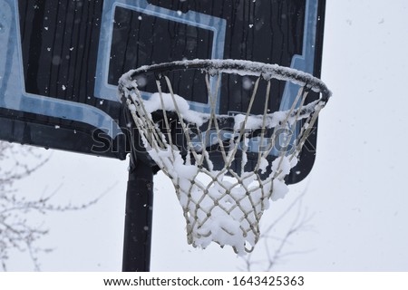 Basketball hoop and net covered in snow