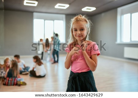 Relaxation time. Portrait of a little happy girl looking at camera and smiling while standing in the dance studio. Choreography class. Activity and hobbies. Sport concept
