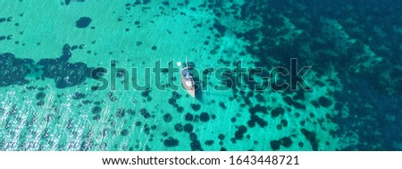 Aerial drone ultra wide photo of sail boat docked in tropical exotic bay with emerald coral reef