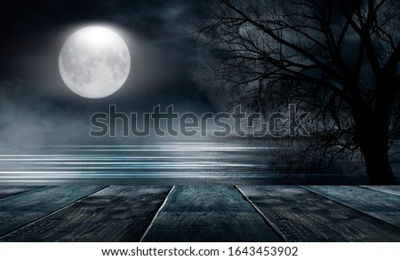 Night landscape and wooden table. Moonlight reflected on the water. Trees, dark street, wet asphalt.