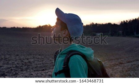 funny boy with backpack walking at sunset outdoors, travel concept