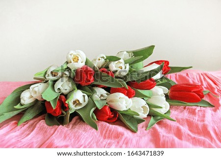 bouquet of red and white tulips on the table on a pink background