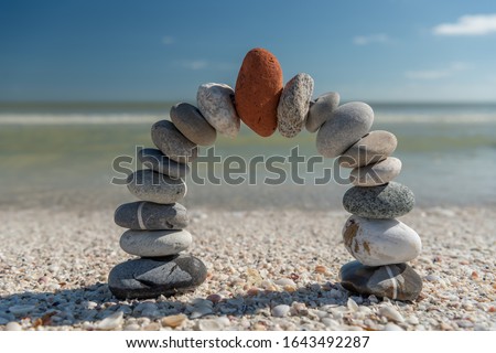 Stone arch with red stone at top in the morning on a beach