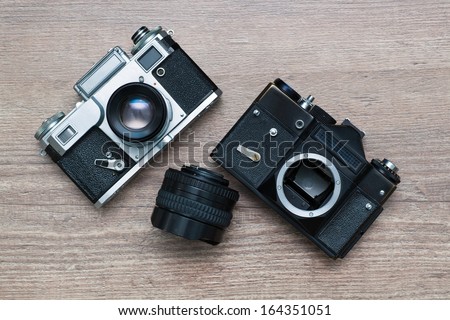 two vintage photo camera and lens on a wooden background Royalty-Free Stock Photo #164351051