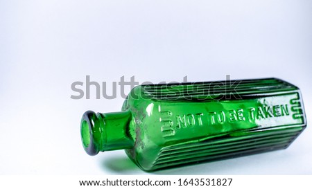 Green victorian home use chemicals bottle, Not to be taken sign, vintage glassware oldtimes common household item on white background with copy space
