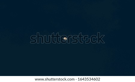 dark blue night sky with yellow crescent in the center with starless catters
