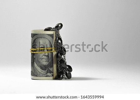 
Dollars twisted into a tube are tied with a yellow rubber band for money. Decorated with gray stone jewelry. Suitable for backgrounds and financial cards.