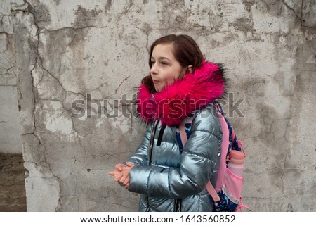 Girl 9 years old with a school backpack on her back. Portrait of a schoolgirl 9 years old. 4th grade school. Girl on the street.