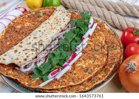 Lahmacun traditional Turkish pizza with salad isolated on rustic wooden table.