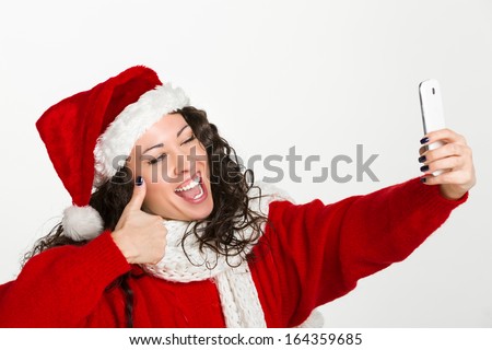 Attractive brunette santa girl taking self portrait with a smart phone in ok gesture