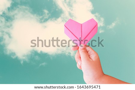 A child holding a paper heart on an isolated background