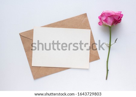 Minimalistic card mockup with roses. craft envelope, white flowers, branches, flat lay, top view. wedding invitation