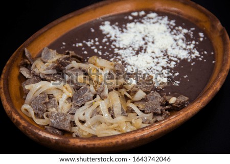 Mexican breakfast with beef and onion slices and refried black beans