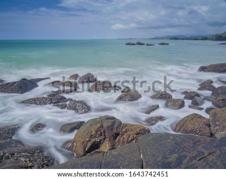 view seaside of silky wave attack many arch rocks with blue-green sea and cloudy sky background, Khao Lak-Lam Ru National Park, Phang Nga, southern of Thailand.