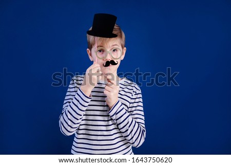 Birthday party and young boy with glasses in hats and props on blue background.