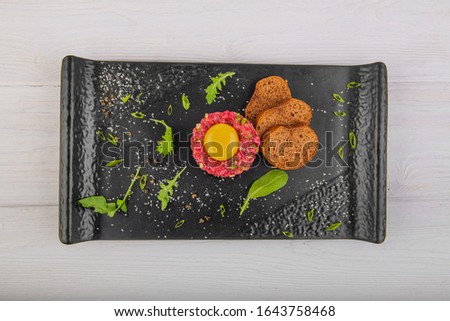 tartar with yolk on a white wooden background