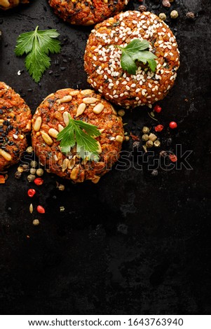 Vegan burgers, baked vegan burgers, cutlets made of carrots, millet, mix of seeds herbs and spices  on dark background, top view, copy space. Healthy eating concept