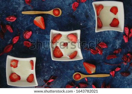 picture of three bowls with cream and strawberries you can also see some wooden spoons