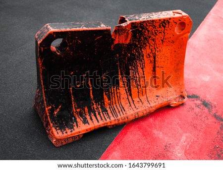 Orange dirty safety barrier on the road. Red painted asphalt. Red road surface marking.