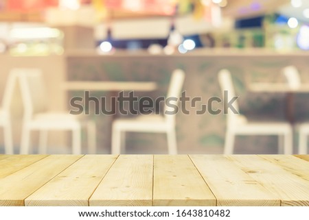 Food court or food center in shopping mall. Interior consist of table, chair, restaurant, coffee shop. Similar of canteen for shopping mall. Wood table top for product display or blurred background.