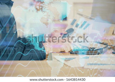 Double exposure of graph with man typing on computer in office on background. Concept of hard work. Closeup.