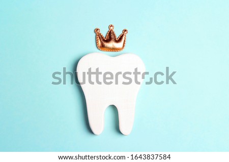 Tooth in the crown on a blue background. Happy Dentist's Day concept.