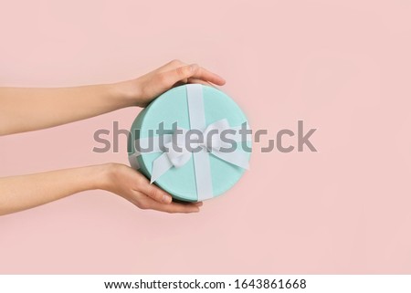 Female hands with beautiful gift box on color background