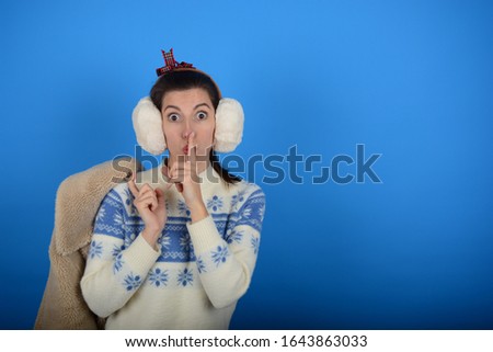 woman holds fur coat finger at mouth on blue background silence emotions